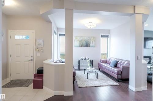 Bright living area featuring wood-finish flooring, abundant natural light from multiple windows, and a tiled entryway - 1728 53 Street, Edmonton, AB - Indoor