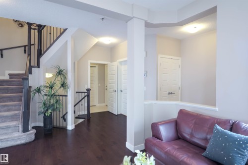 Spacious entryway featuring dark wood-finish flooring, a carpeted staircase with dark wood handrails and wrought iron balusters, and recessed ceiling lights - 1728 53 Street, Edmonton, AB - Indoor Photo Showing Other Room