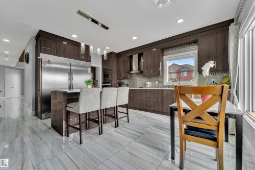 Modern kitchen featuring wood-finish cabinetry, stainless steel appliances, and a mosaic tile backsplash - 1404 25 Street, Edmonton, AB - Indoor