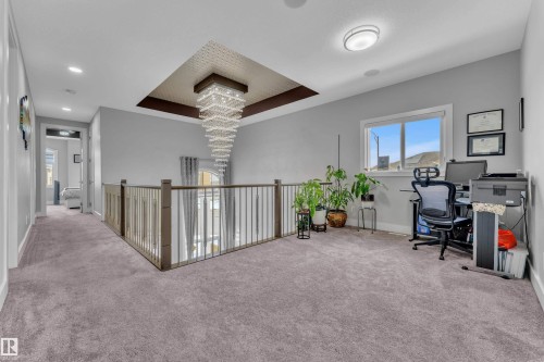 Upper-level landing featuring a contemporary chandelier, open railing, recessed lighting, a large window, and light grey carpeting - 1404 25 Street, Edmonton, AB - Indoor