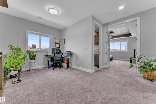 Spacious carpeted landing featuring built-in cabinetry with sink, an open doorway to an additional room, and windows providing natural light - 1404 25 Street, Edmonton, AB - Indoor