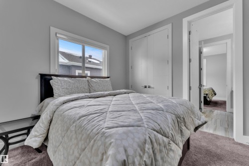 Bedroom featuring a large window, neutral gray walls, a built-in closet with double doors, and soft brown carpeting - 1404 25 Street, Edmonton, AB - Indoor Photo Showing Bedroom