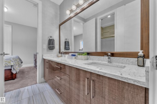 Double vanity featuring a wood-finish cabinet, stone countertop, integrated sinks, and individual chrome faucets - 1404 25 Street, Edmonton, AB - Indoor Photo Showing Bathroom