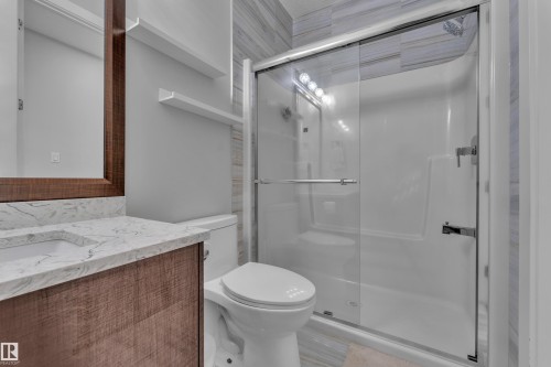 Bathroom featuring a glass-enclosed shower with a multi-piece surround and tile accent wall - 1404 25 Street, Edmonton, AB - Indoor Photo Showing Bathroom