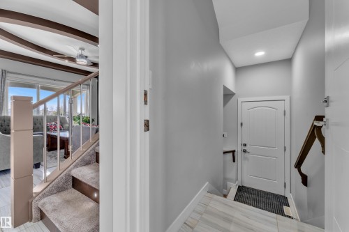 Foyer featuring marble-look tile flooring, a white paneled door, and a wooden handrail - 1404 25 Street, Edmonton, AB - Indoor Photo Showing Other Room