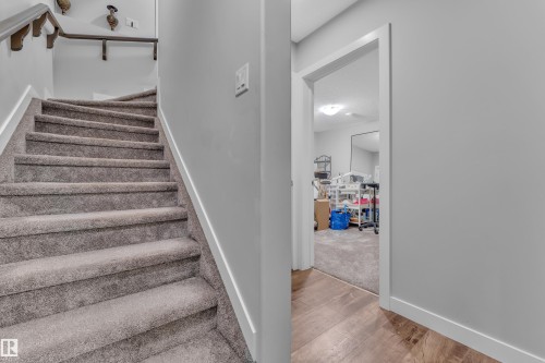 Staircase with gray carpeted treads and white trim, featuring a dark wood-finish handrail - 1404 25 Street, Edmonton, AB - Indoor Photo Showing Other Room