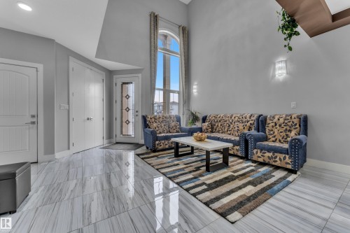 Two-story living area featuring high ceilings, wood-finish flooring, and a decorative arched window - 1404 25 Street, Edmonton, AB - Indoor Photo Showing Living Room