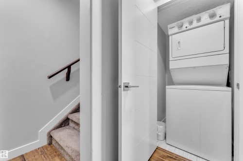 Dedicated laundry closet with a stackable washer and dryer, featuring a panel-style door with a chrome lever handle - 1404 25 Street, Edmonton, AB - Indoor Photo Showing Laundry Room