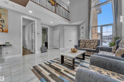 Two-story living area featuring large windows, high ceilings, recessed lighting, and polished tile flooring - 1404 25 Street, Edmonton, AB - Indoor Photo Showing Living Room