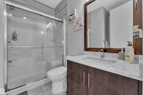 Bathroom vanity featuring a light-toned countertop with an integrated sink, dark wood-finish cabinetry, and a framed mirror - 1404 25 Street, Edmonton, AB - Indoor Photo Showing Bathroom