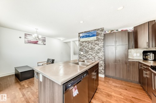 Kitchen featuring a double basin stainless steel sink, a built-in dishwasher, and wood-finish cabinetry with brushed nickel hardware - 69 3625 144 Avenue, Edmonton, AB - Indoor Photo Showing Kitchen With Double Sink