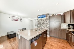 Kitchen featuring a double basin stainless steel sink, a built-in dishwasher, and wood-finish cabinetry with brushed nickel hardware - 
