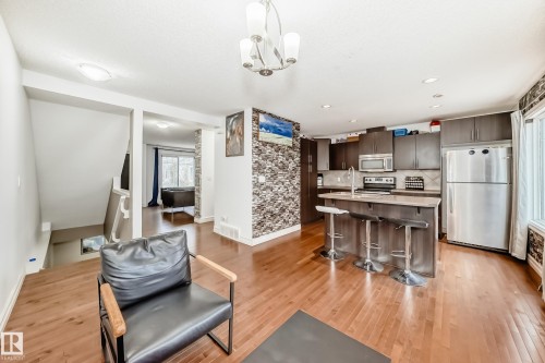 Open-concept kitchen featuring dark wood-finish cabinetry, stainless steel appliances, a center island with bar seating, and recessed lighting - 69 3625 144 Avenue, Edmonton, AB - Indoor