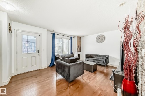 Spacious living area featuring light wood-finish flooring, white walls, and a white paneled entry door with clear glass - 69 3625 144 Avenue, Edmonton, AB - Indoor Photo Showing Living Room