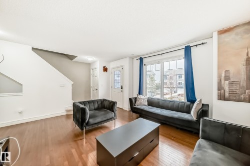 Spacious living area featuring wood-finish flooring, white painted walls, and a large multi-pane window - 69 3625 144 Avenue, Edmonton, AB - Indoor Photo Showing Living Room