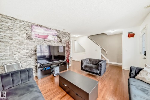 Living area featuring wood-finish flooring, a stone-effect accent wall, and recessed lighting - 69 3625 144 Avenue, Edmonton, AB - Indoor Photo Showing Living Room