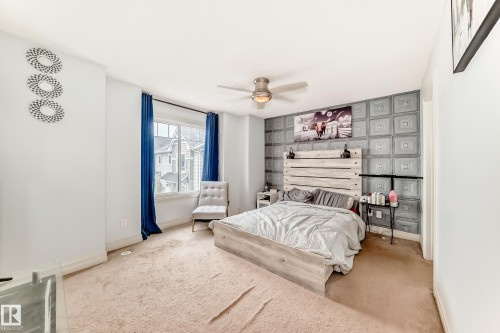 Carpeted bedroom with a window, a ceiling fan, and a textured accent wall - 69 3625 144 Avenue, Edmonton, AB - Indoor Photo Showing Bedroom