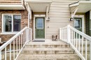 Entryway featuring concrete steps with white railings, a green paneled door with window inserts, and sconce lighting - 69 3625 144 Avenue, Edmonton, AB  - Outdoor With Deck Patio Veranda With Exterior 