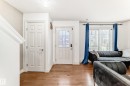 Hardwood-finish flooring throughout, featuring a white paneled door, a glass-paneled entry door, and a large sliding glass door with transom window - 69 3625 144 Avenue, Edmonton, AB  - Indoor 