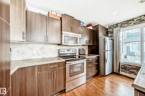 Kitchen featuring stainless steel appliances, wood-finish flooring, and dark cabinetry - 69 3625 144 Avenue, Edmonton, AB - Indoor Photo Showing Kitchen