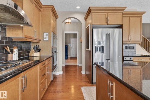 Kitchen featuring wood-finish cabinetry, black countertops, and a subway tile backsplash - 1110 Armitage Crescent, Edmonton, AB - Indoor Photo Showing Kitchen