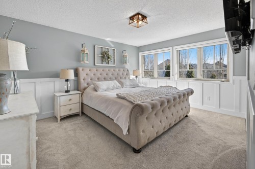 Carpeted bedroom featuring multiple windows, wainscoting, and a ceiling-mounted light fixture - 1110 Armitage Crescent, Edmonton, AB - Indoor Photo Showing Bedroom