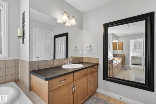 Bathroom featuring double vanities with wood-finish cabinetry and dark countertops - 1110 Armitage Crescent, Edmonton, AB - Indoor Photo Showing Bathroom