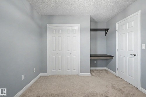 Room featuring light-toned carpet flooring, white bi-fold closet doors, and a built in desk ba - 1110 Armitage Crescent, Edmonton, AB - Indoor
