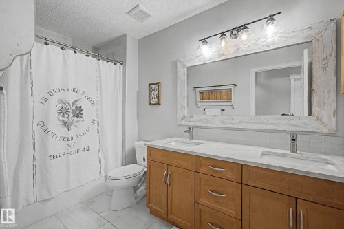 Dual vanity with light wood-finish cabinetry and integrated sinks set into a light-toned countertop - 1110 Armitage Crescent, Edmonton, AB - Indoor Photo Showing Bathroom