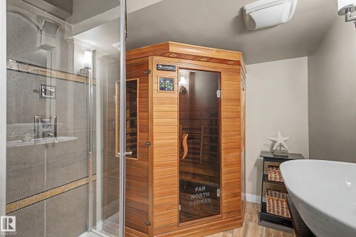 Dedicated sauna unit, glass-enclosed shower with tiled surround, rainfall showerhead, wall-mounted light fixture, and tile flooring - 1110 Armitage Crescent, Edmonton, AB - Indoor Photo Showing Bathroom