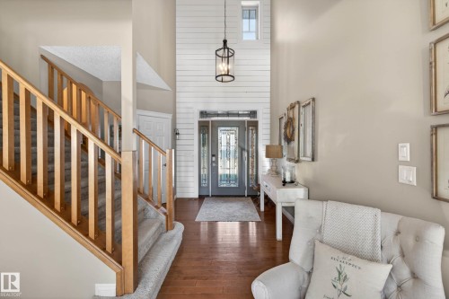 Two-story foyer featuring shiplap accent wall, hardwood flooring, and a decorative front entry door with transom window - 1110 Armitage Crescent, Edmonton, AB - Indoor Photo Showing Other Room