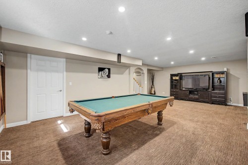 Basement living area bawith textured carpet flooring, recessed lighting, and a white paneled door - 1110 Armitage Crescent, Edmonton, AB 