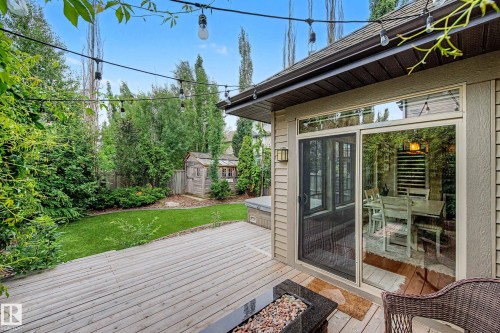 Expansive wooden deck with string lighting, overlooking a manicured lawn and mature trees - 1110 Armitage Crescent, Edmonton, AB 