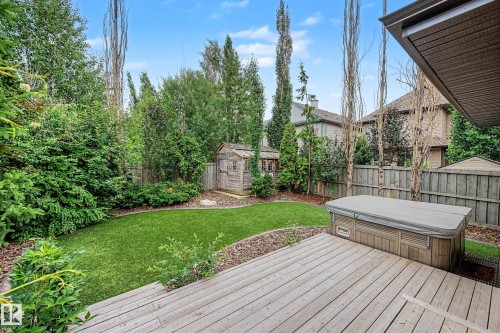 Expansive backyard featuring a large wooden deck with a built-in spa, a manicured lawn, and mature trees providing natural screening - 1110 Armitage Crescent, Edmonton, AB 