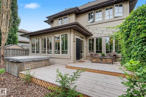 Expansive tiered wood deck featuring a built-in hot tub and a stone fire table - 1110 Armitage Crescent, Edmonton, AB 