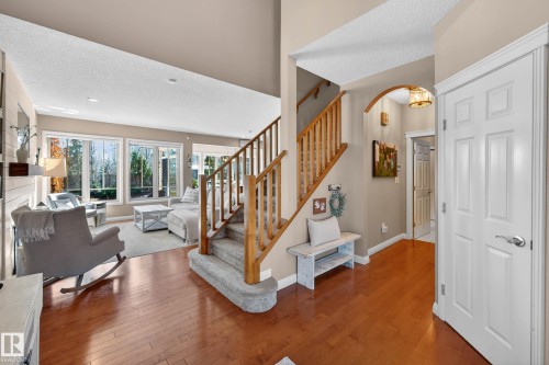 Foyer with hardwood flooring, a carpeted staircase with wood railings, and a white panel door - 1110 Armitage Crescent, Edmonton, AB - Indoor With Fireplace