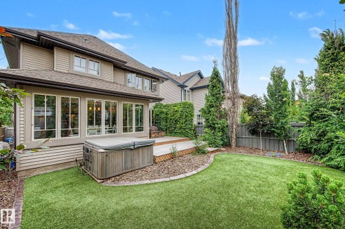 Expansive backyard featuring a manicured lawn, a wooden deck, and mature perimeter trees - 1110 Armitage Crescent, Edmonton, AB 