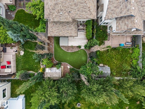Expansive backyard featuring a curvilinear artificial turf lawn, shed, mature trees, and a wooden deck - 1110 Armitage Crescent, Edmonton, AB 