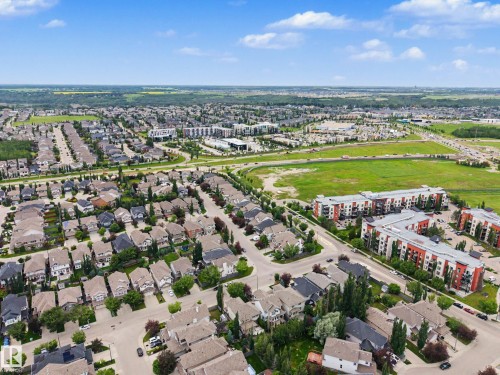 Expansive aerial showcasing a residential community with single-family homes, multi-story apartment buildings, green spaces, and commercial developments - 1110 Armitage Crescent, Edmonton, AB 