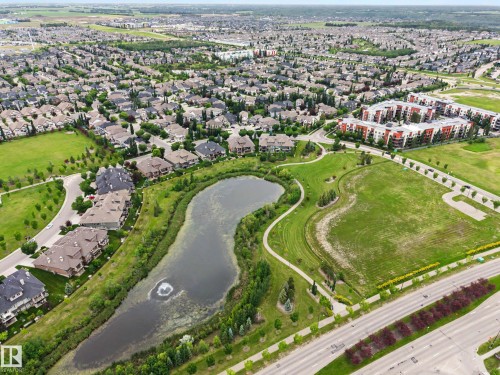 Expansive neighborhood featuring residential homes, a large pond with a water feature, green spaces, and paved pathways - 1110 Armitage Crescent, Edmonton, AB 