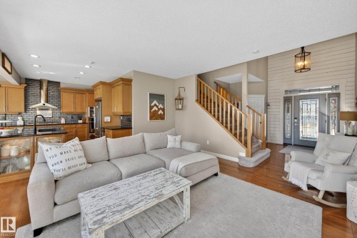 Open-concept living area featuring hardwood flooring, a two-story foyer with shiplap accent wall, and a staircase with wood railings - 1110 Armitage Crescent, Edmonton, AB - Indoor Photo Showing Living Room