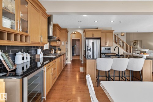 Gourmet kitchen featuring wood cabinetry, black subway tile backsplash, stainless steel appliances, and a beverage cooler - 1110 Armitage Crescent, Edmonton, AB - Indoor Photo Showing Kitchen With Upgraded Kitchen