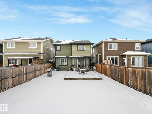 Rear elevation featuring a wood deck, sliding glass doors, multiple windows, and a wood privacy fence - 21851 80 Avenue, Edmonton, AB - Outdoor With Exterior