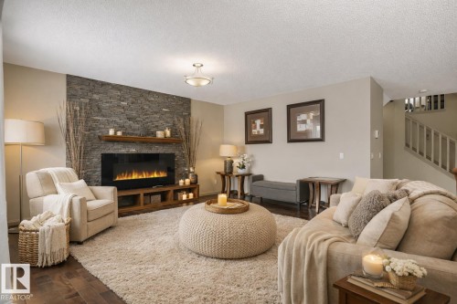 Living space featuring a stone accent wall with a built-in electric fireplace and wood-finish mantle - 21851 80 Avenue, Edmonton, AB - Indoor Photo Showing Living Room With Fireplace