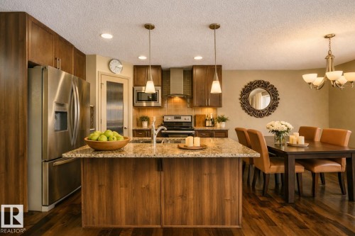 Kitchen island featuring a granite-style countertop, undermount sink, and two pendant lights - 21851 80 Avenue, Edmonton, AB - Indoor