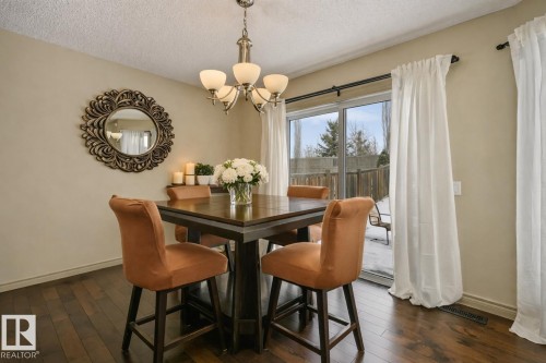 Dining area featuring wood-finish flooring, a contemporary chandelier, and light-toned walls - 21851 80 Avenue, Edmonton, AB - Indoor Photo Showing Dining Room
