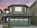 Two-story residence featuring green horizontal siding, a dark asphalt shingle roof, and a prominent attached garage with a matching green door - 21851 80 Avenue, Edmonton, AB  - Outdoor With Exterior 