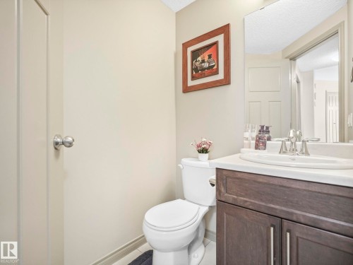 Powder room featuring a wood-finish vanity with a white countertop and undermount sink - 21851 80 Avenue, Edmonton, AB - Indoor Photo Showing Bathroom