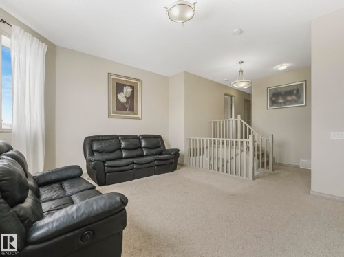 Carpeted landing area featuring a light-toned staircase with white balusters - 21851 80 Avenue, Edmonton, AB - Indoor Photo Showing Living Room