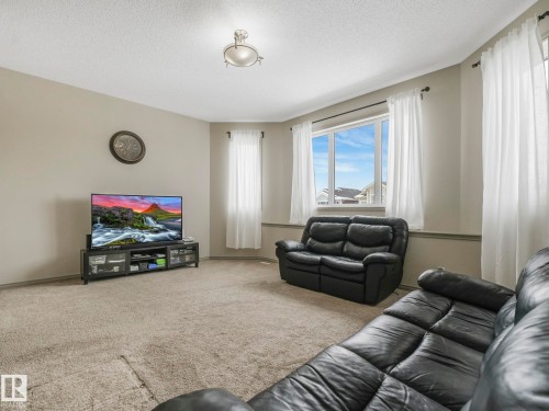 Recessed ceiling lighting illuminates a spacious room featuring a neutral color palette, bay window, and light-toned carpeting - 21851 80 Avenue, Edmonton, AB - Indoor Photo Showing Living Room